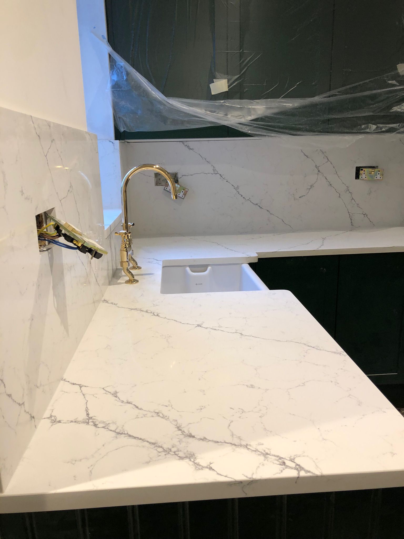 White marble worktop with brass tap and dark cabinetry